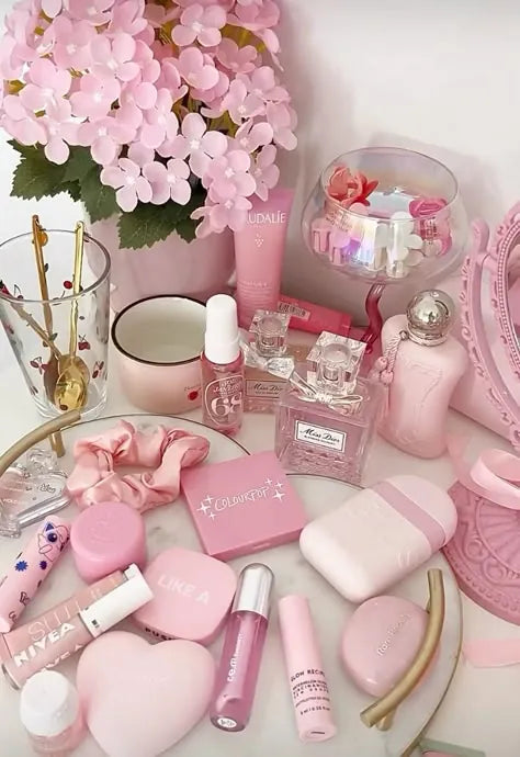 Girly pop collection featuring pink lipstick, eyeshadow palette, perfume, lip gloss, and lip balm on a white surface