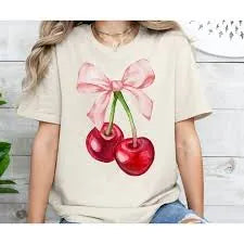 Person wearing a white t-shirt with a vibrant pink bow and cherry graphic design against a white background.